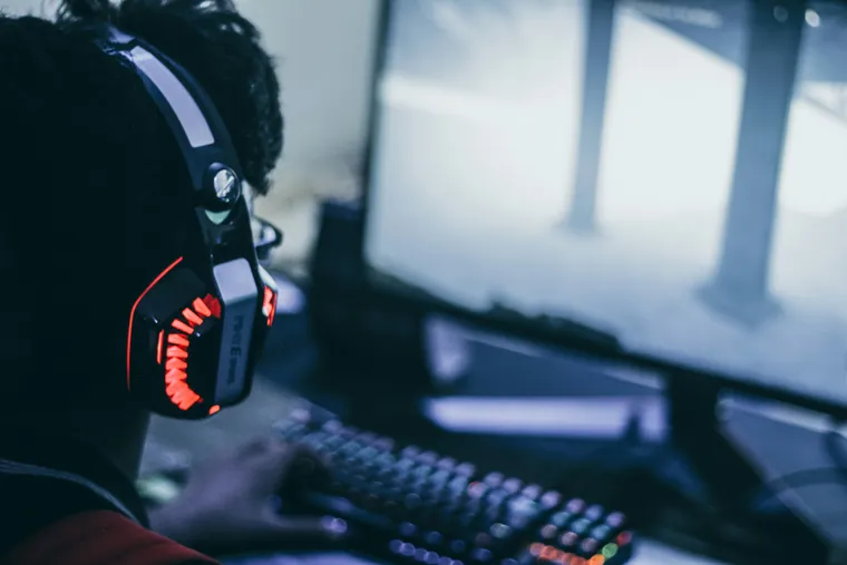 Open-back audiophile headphones on a desk beside a gaming setup