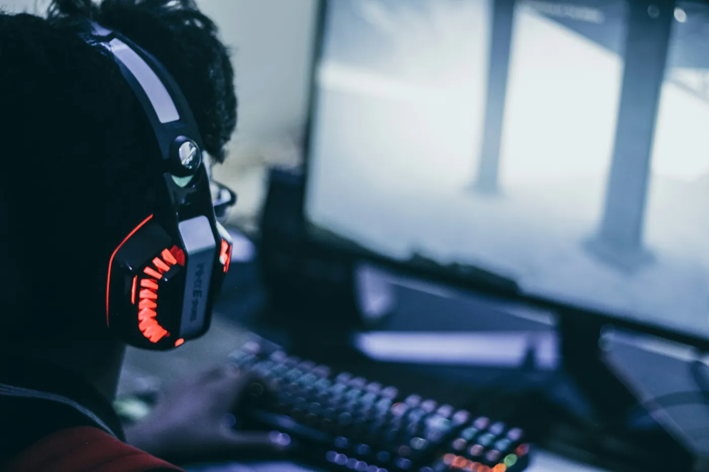Open-back audiophile headphones on a desk beside a gaming setup