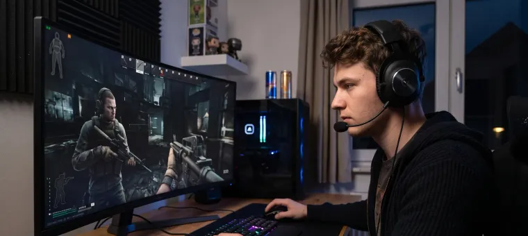 Gamer wearing a headset playing a tactical FPS on an ultrawide monitor at a PC setup